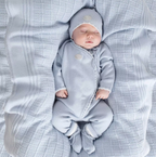 Baby in a gray outfit lying on a textured blanket