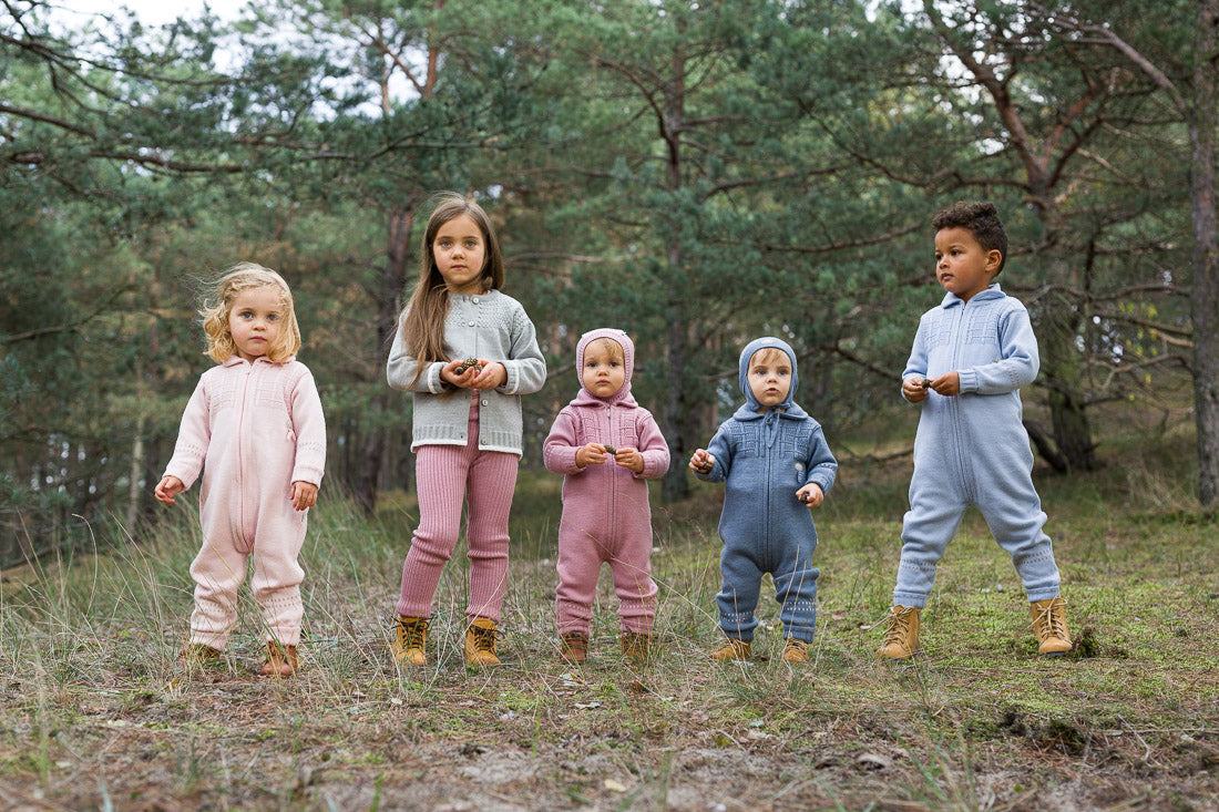 Five children in matching outfits standing in a forest.