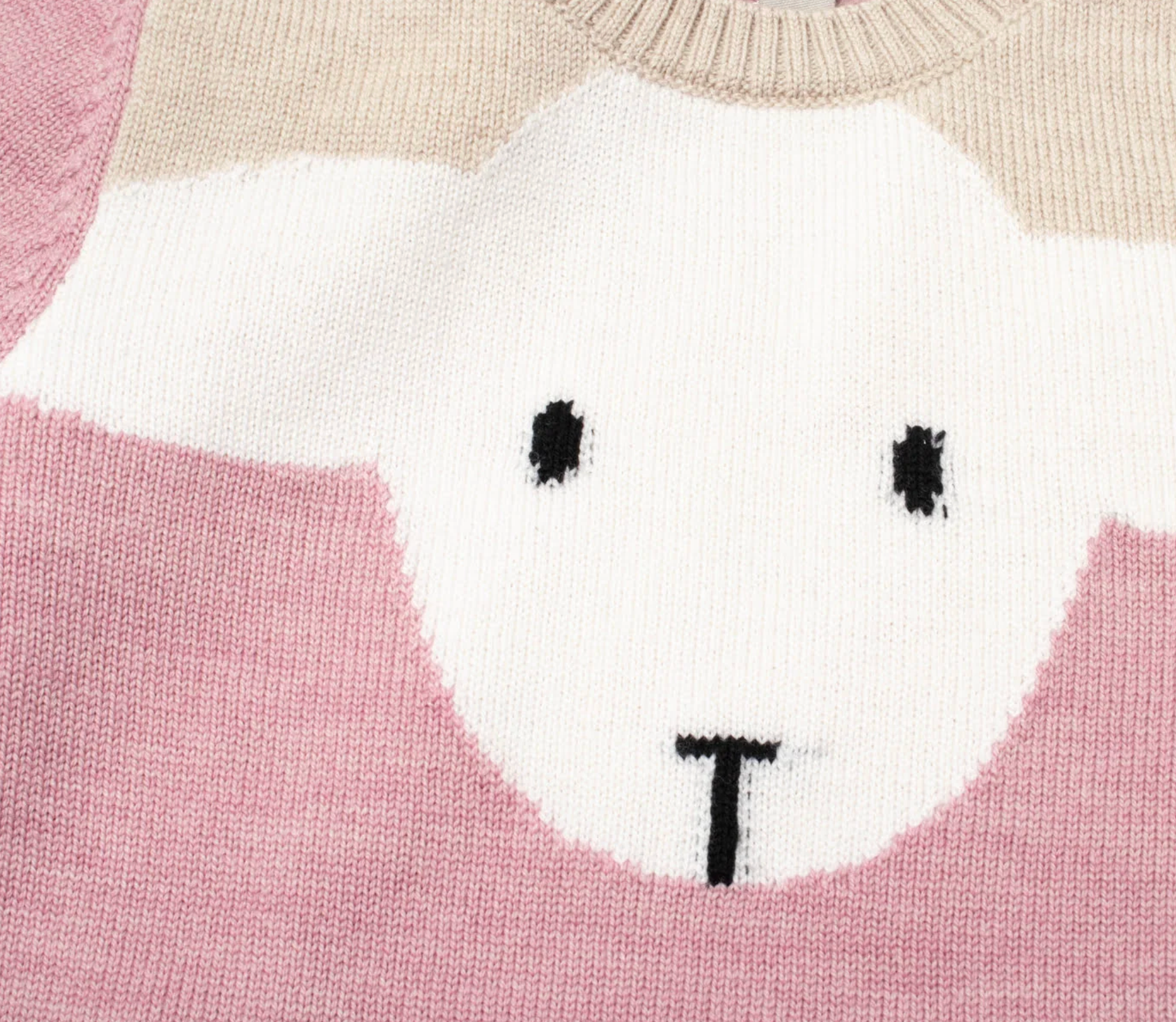 Close-up of a knitted sweater featuring a stylized face with black eyes and a black mouth on a pink and white background, with a beige ribbed collar at the top.